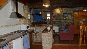 Una cocina rústica con pared de piedra, armarios de madera y un sofá rojo en la sala de estar.