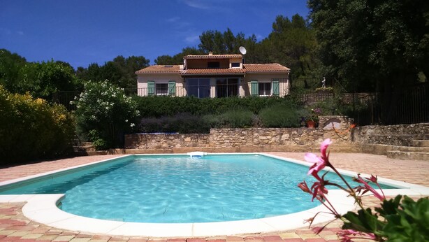 Une piscine rectangulaire avec un mur en pierre et une bordure en briques.
