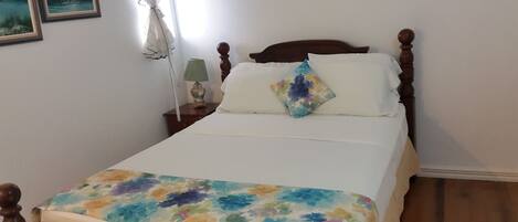 A bed with a floral bedspread, a wooden headboard, and a nightstand with a lamp.
