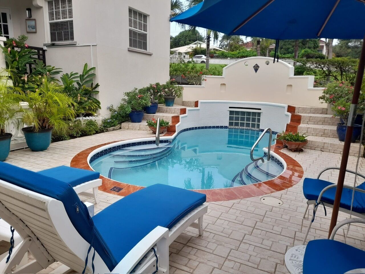 Une piscine entourée de chaises longues bleues et de plantes en pot.