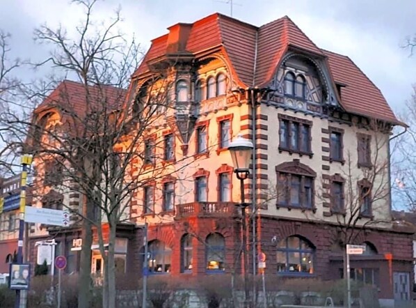 Un bâtiment historique à étages, doté de grandes fenêtres et d’une entrée d’angle remarquable.