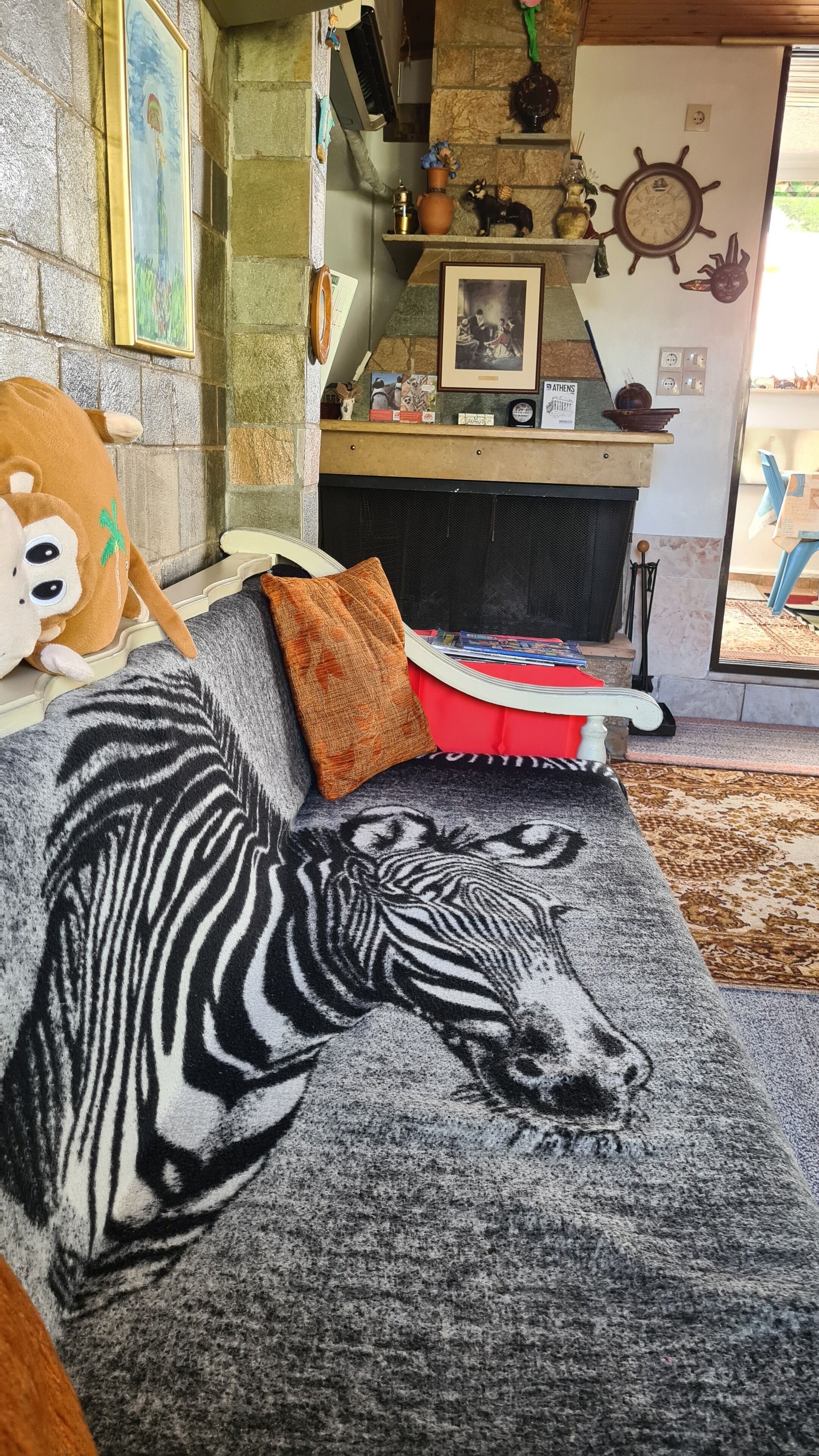 Una sala de estar acogedora con chimenea, un lujoso felpudo de cebra y varios objetos decorativos en estanterías.