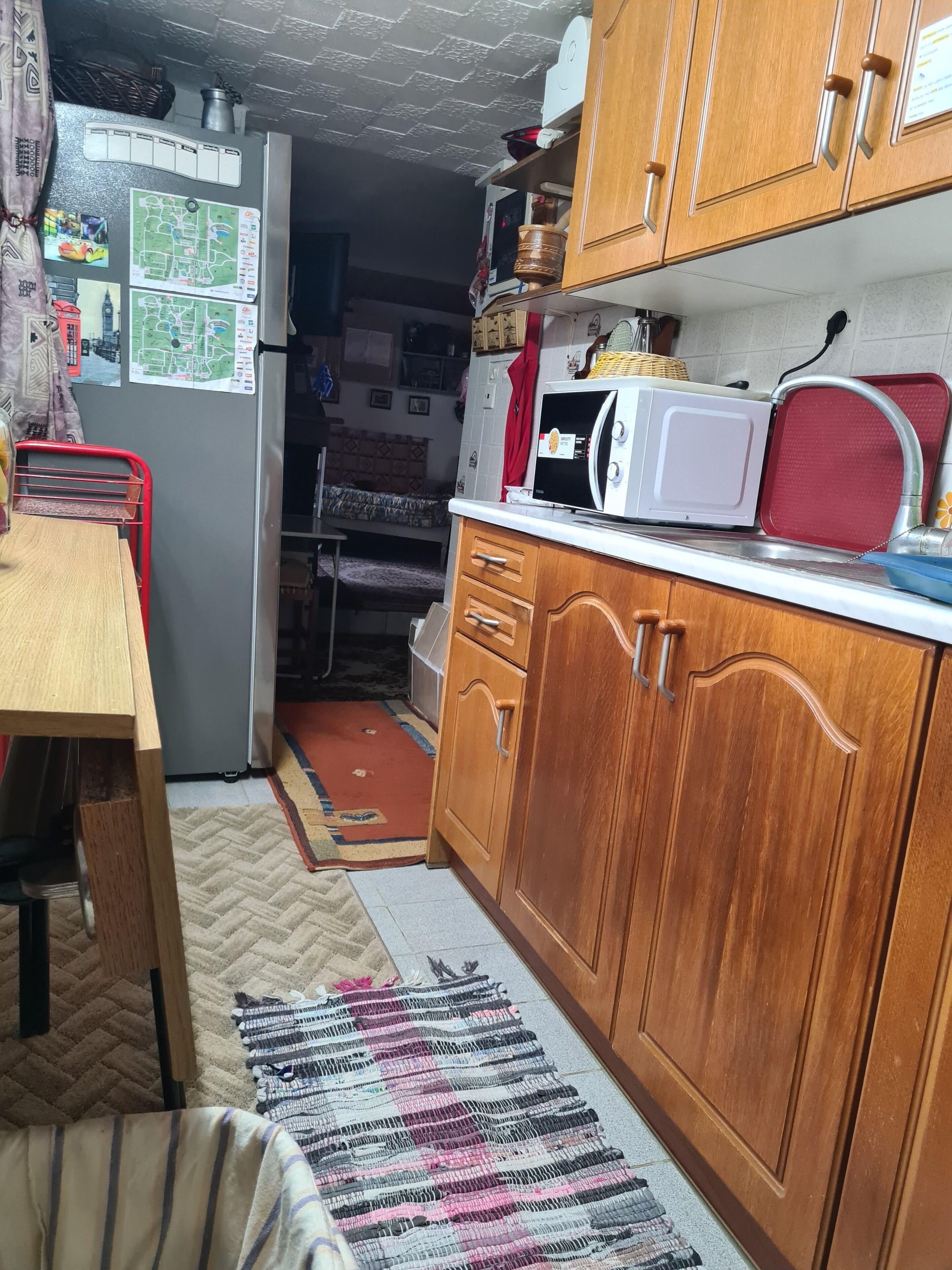 A compact kitchen with wooden cabinets, a microwave, and a refrigerator.
