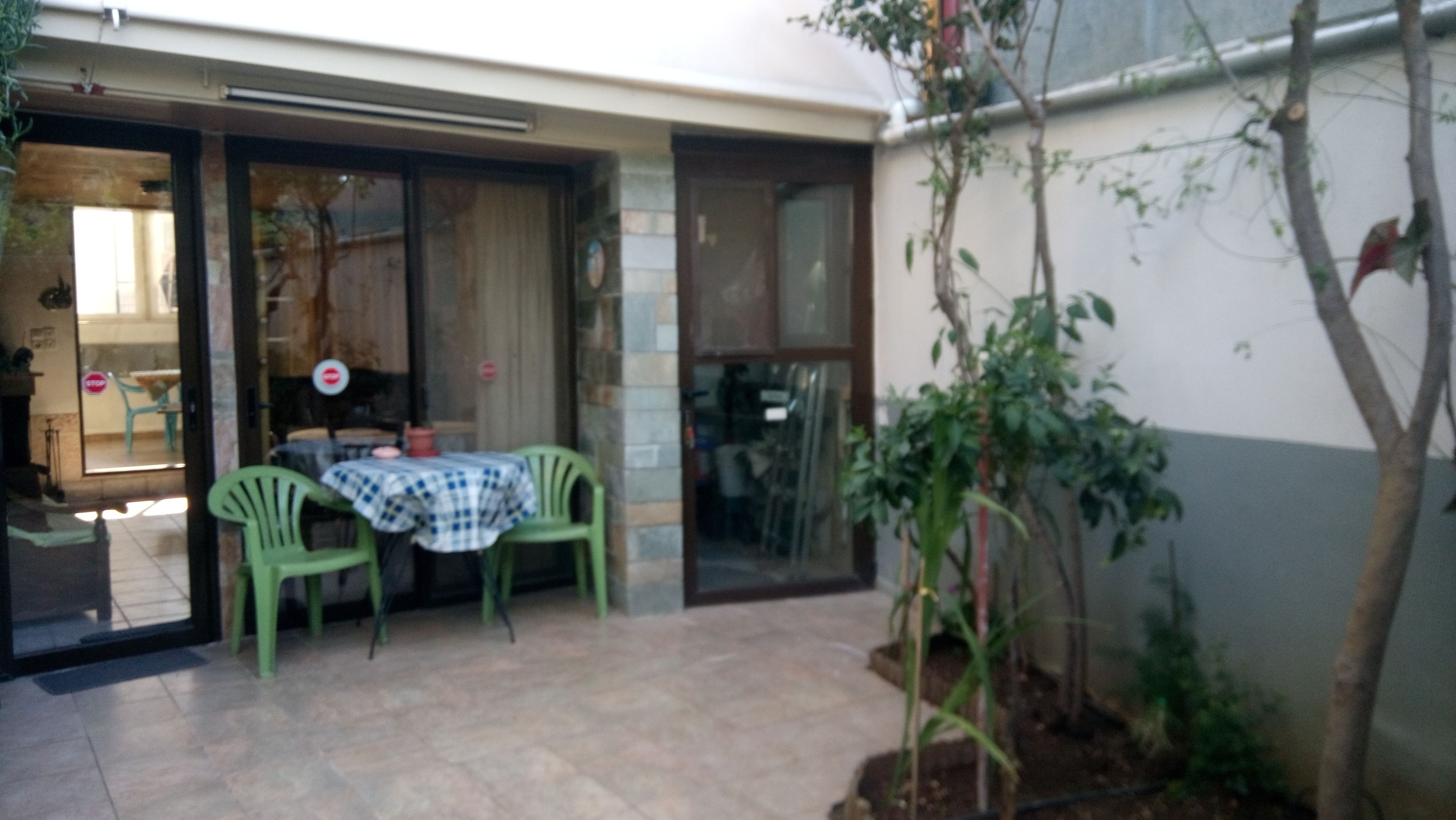 Un patio con tavolo e sedie, una porta e un piccolo giardino.