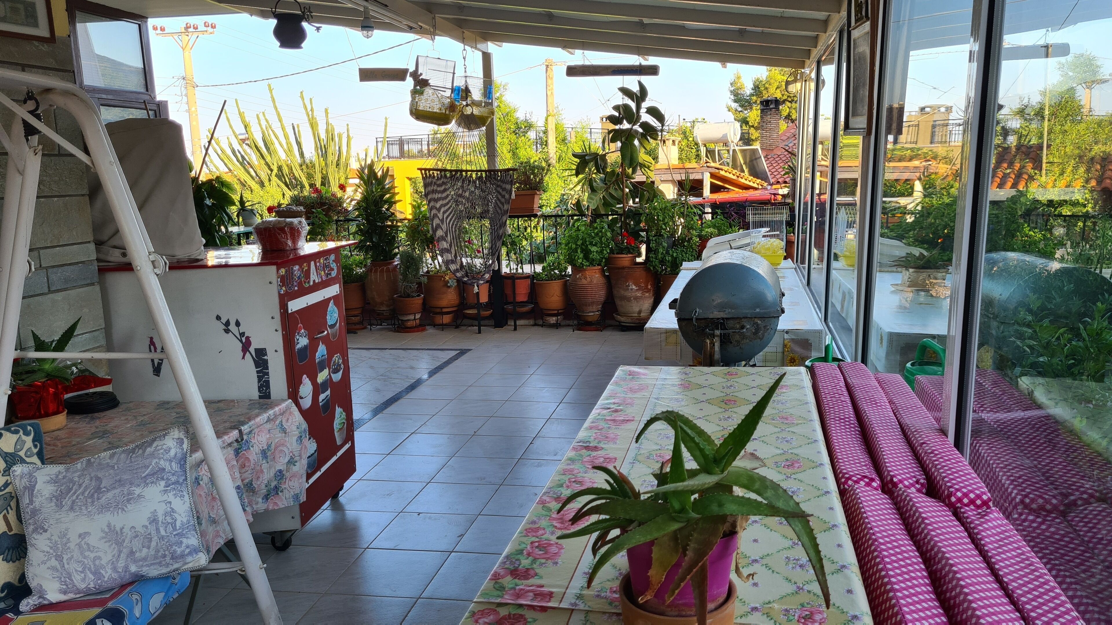 A patio area with a table, chairs, potted plants, and a grill.