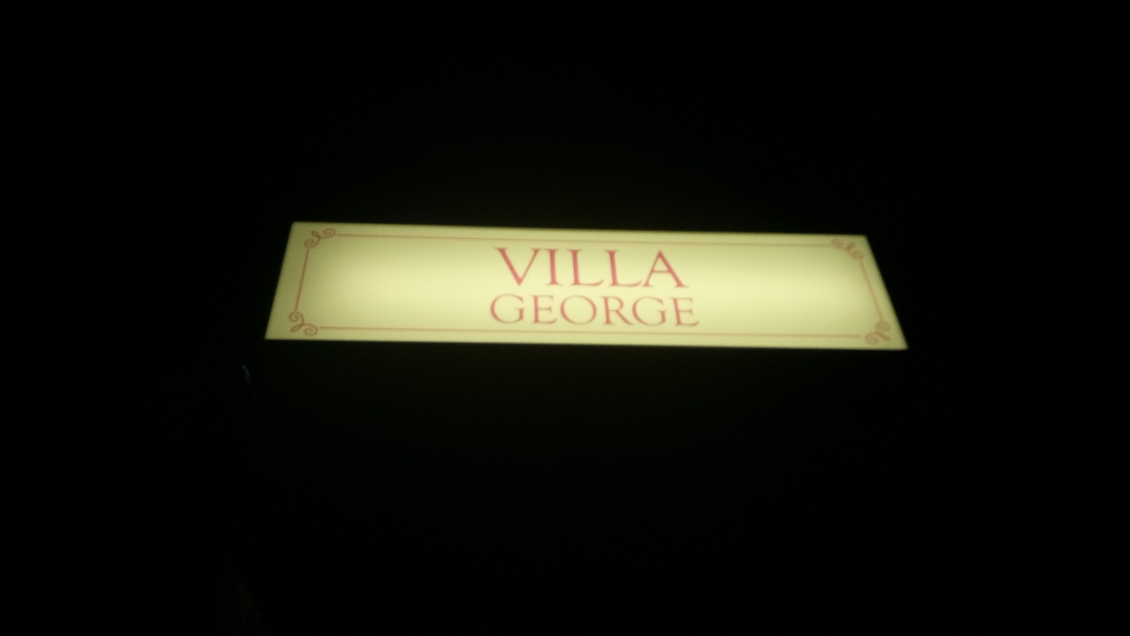 Une enseigne portant l’inscription « VILLA GEORGE », dans un environnement sombre.