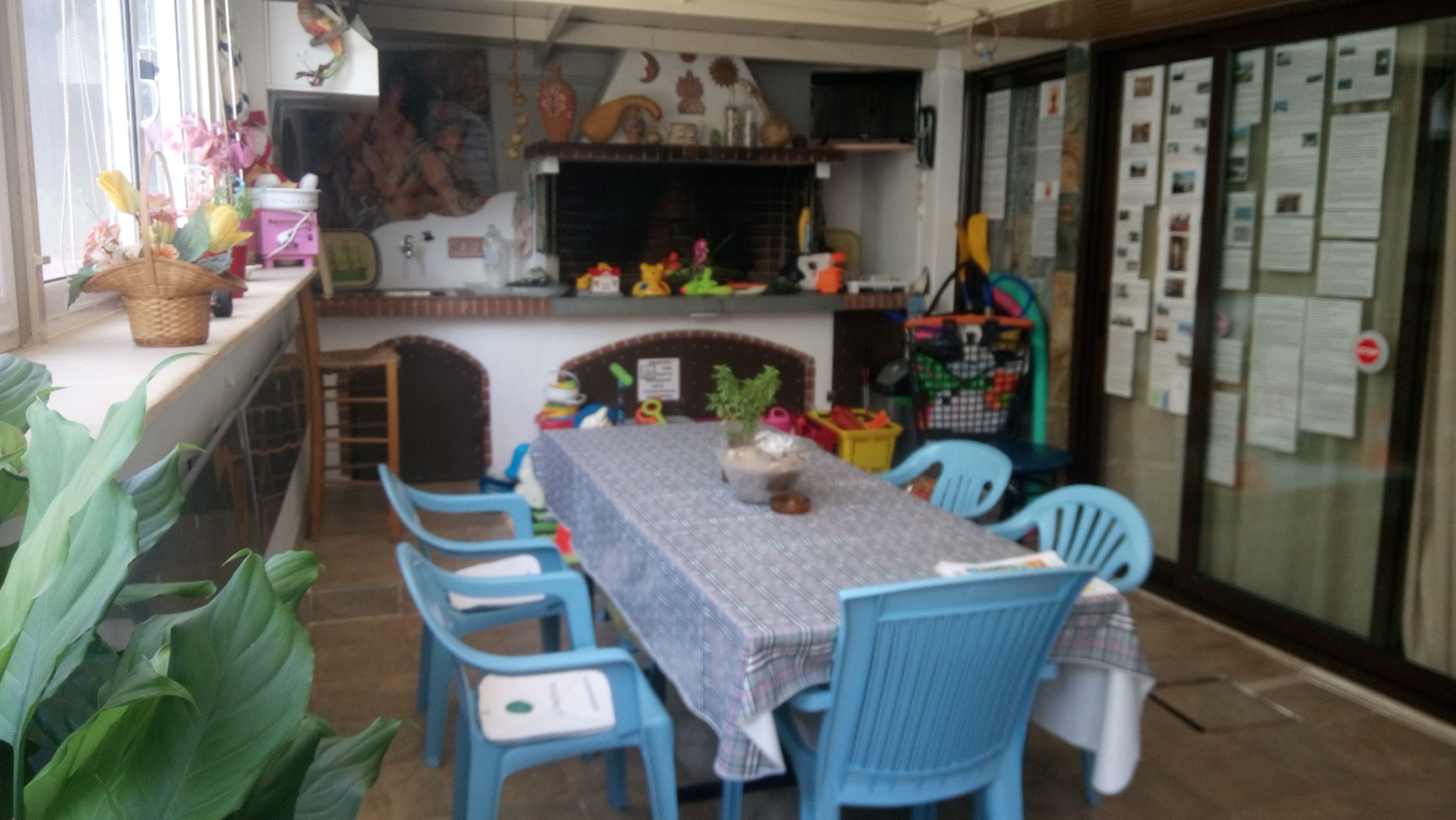 Un comedor con una mesa dispuesta para cuatro, sillas azules y una variedad de juguetes y juegos infantiles.