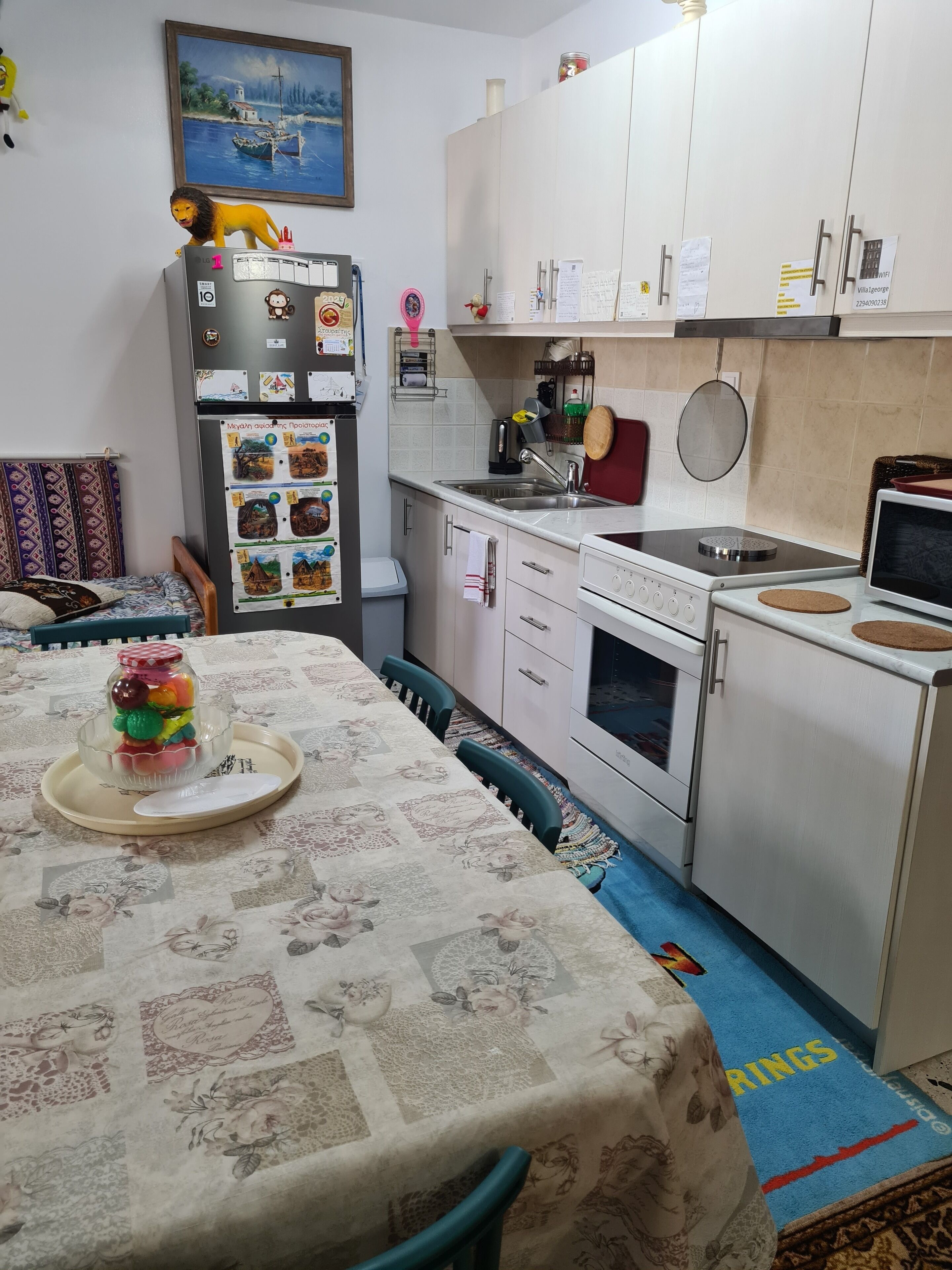 A compact kitchen with a dining area, featuring a refrigerator, stove, sink, and a dining table set with a decorative centerpiece.