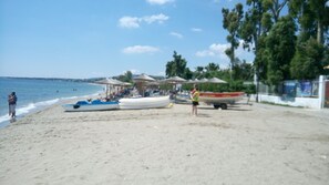 A beach with several boats, umbrellas, and people.