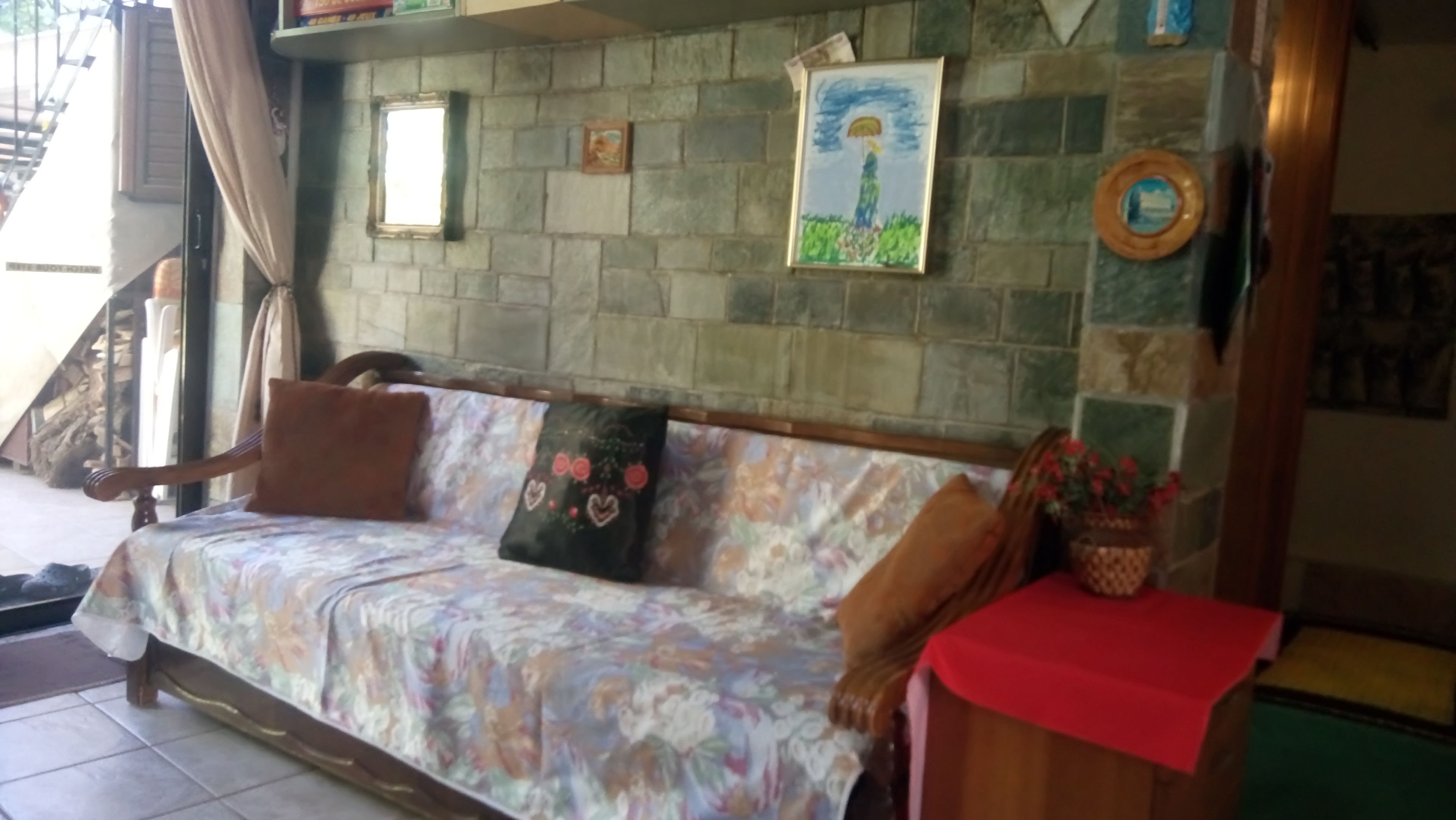 A cozy living area with a sofa, a small table, and a stone wall with artwork.