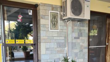 An entrance with a stone wall, a glass door, and a mounted air conditioning unit.