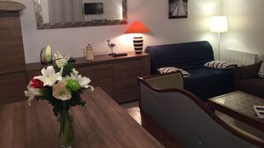 Ein modernes Wohnzimmer mit einem Holztisch, einem blauen Sofa und einem Esstisch mit einem Blumenstrauß.