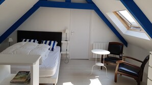 Ein Schlafzimmer mit einem Bett, einem Sessel, einem Tisch und einem Dachfenster.