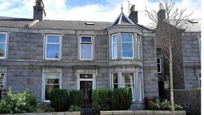 A stone building with a bay window, a door with a sign, and a small garden area. - Apartment To Suit All! Perfect Location With Easy Access To Centre Of Town (Aberdeen)