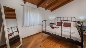 A bedroom with a wooden ceiling, a metal bed frame, white bedding, and a mirror reflecting the room. - Villa with sea view, pool and Breakfast included (Ampoula Beach)