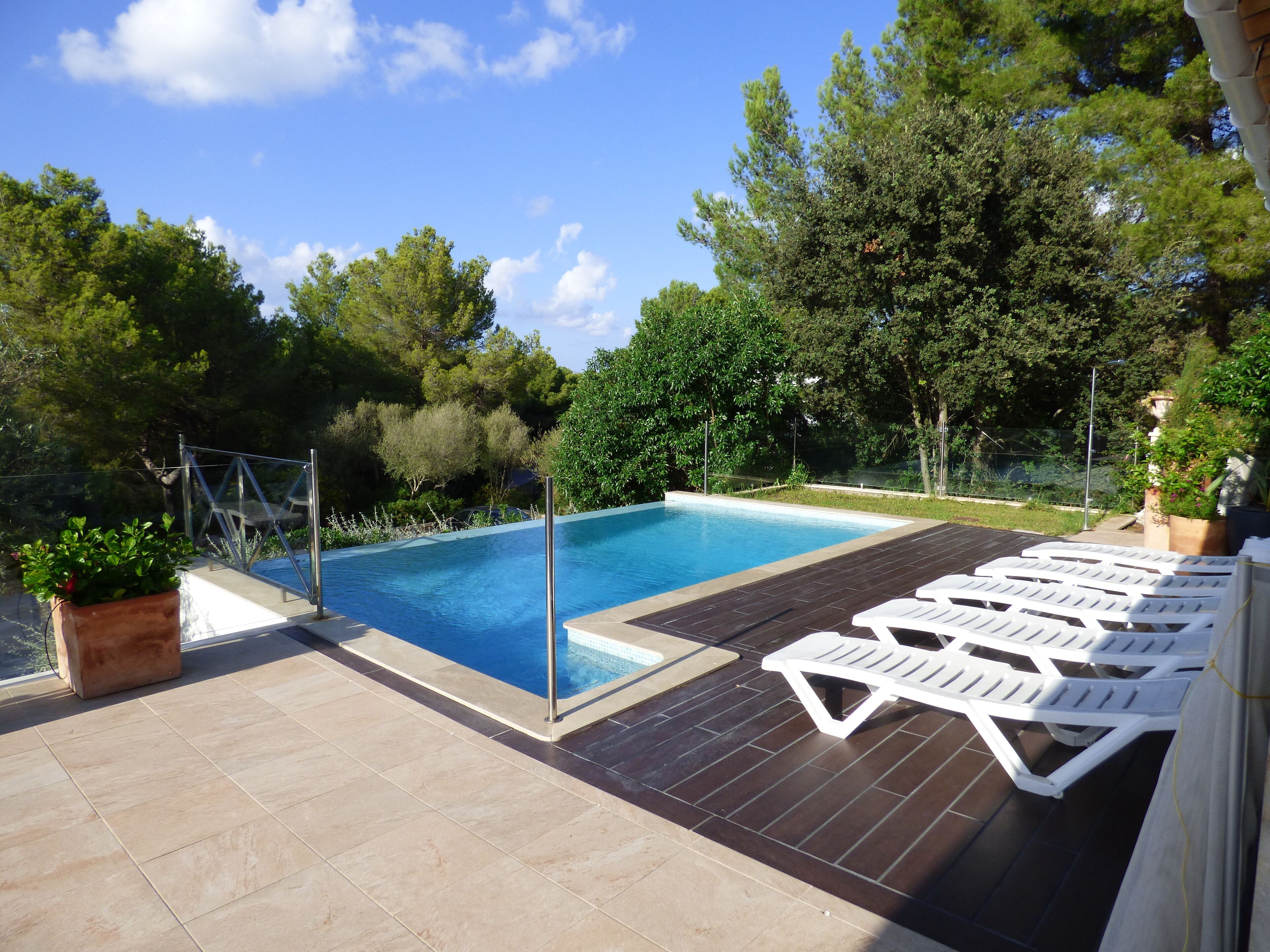 A swimming pool with a tiled deck and lounge chairs.