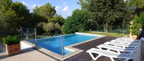A swimming pool with a tiled deck and lounge chairs.