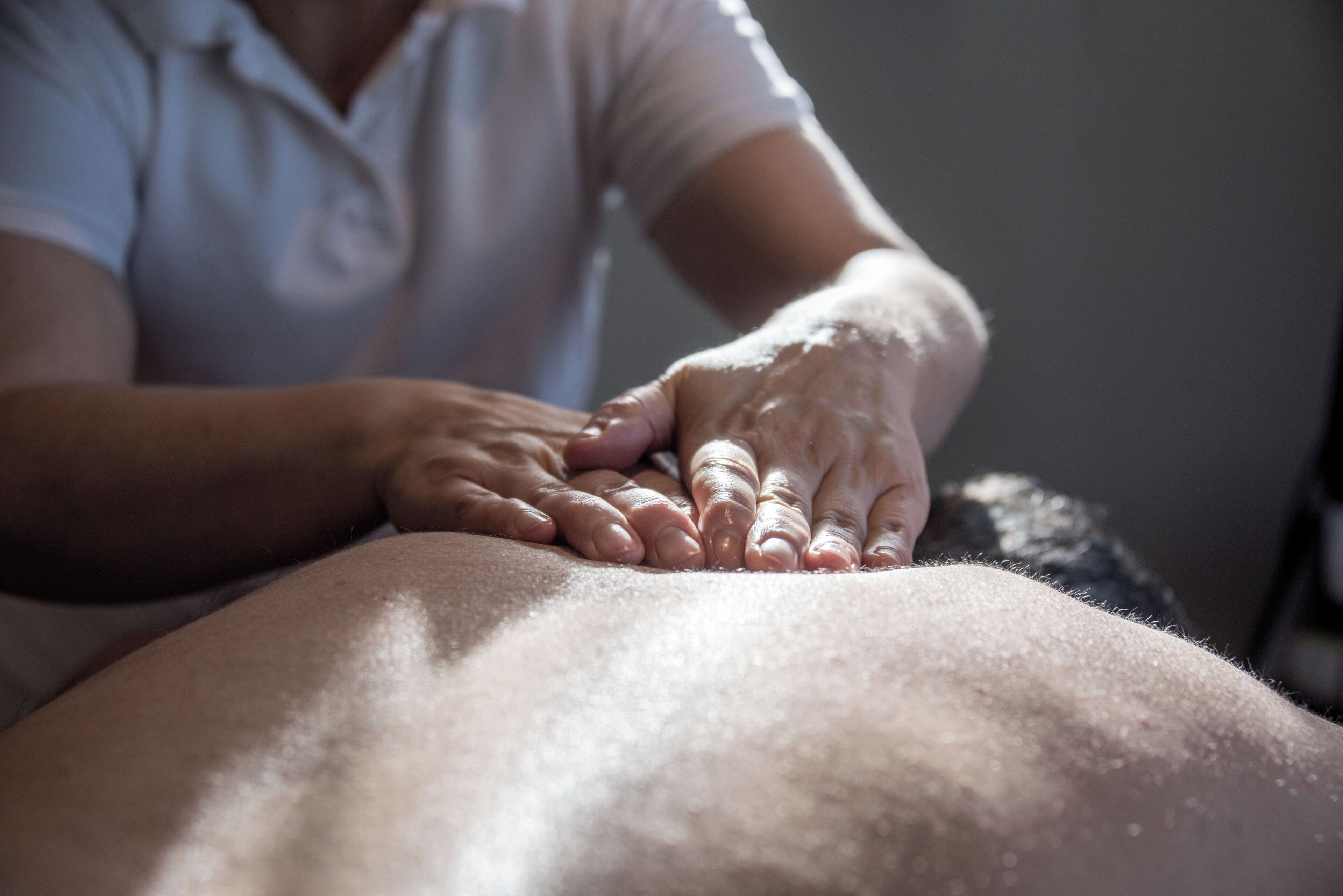 Gros plan sur des mains effectuant un massage sur le dos d’une personne.