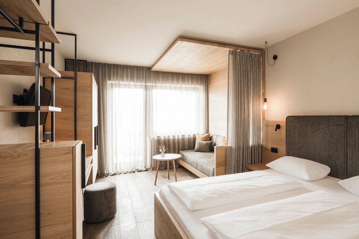 Een hotelkamer met een bed, een bank, een klein tafeltje en een trap.