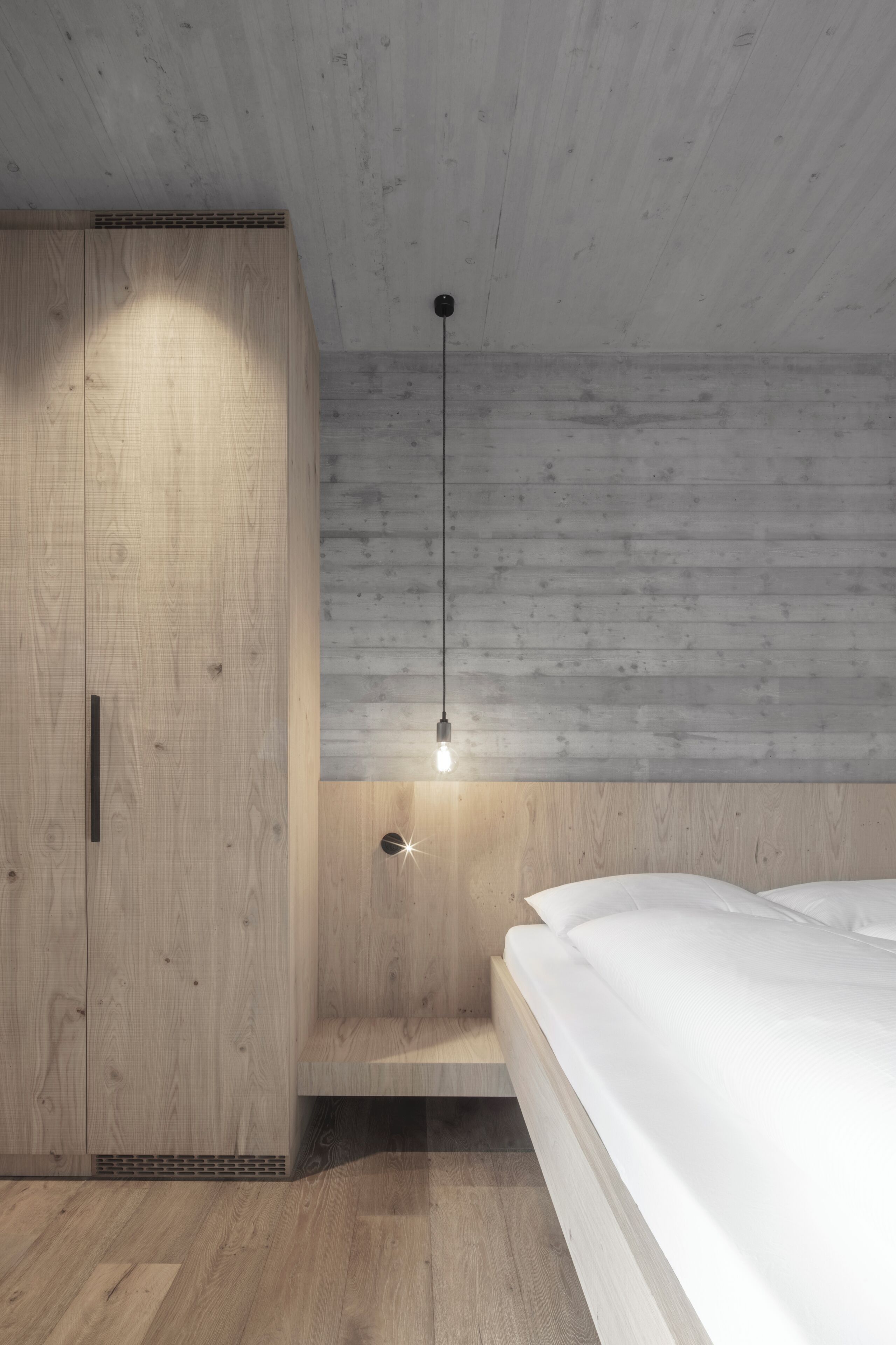 Una camera da letto con un armadio in legno, una lampada a sospensione e un letto.