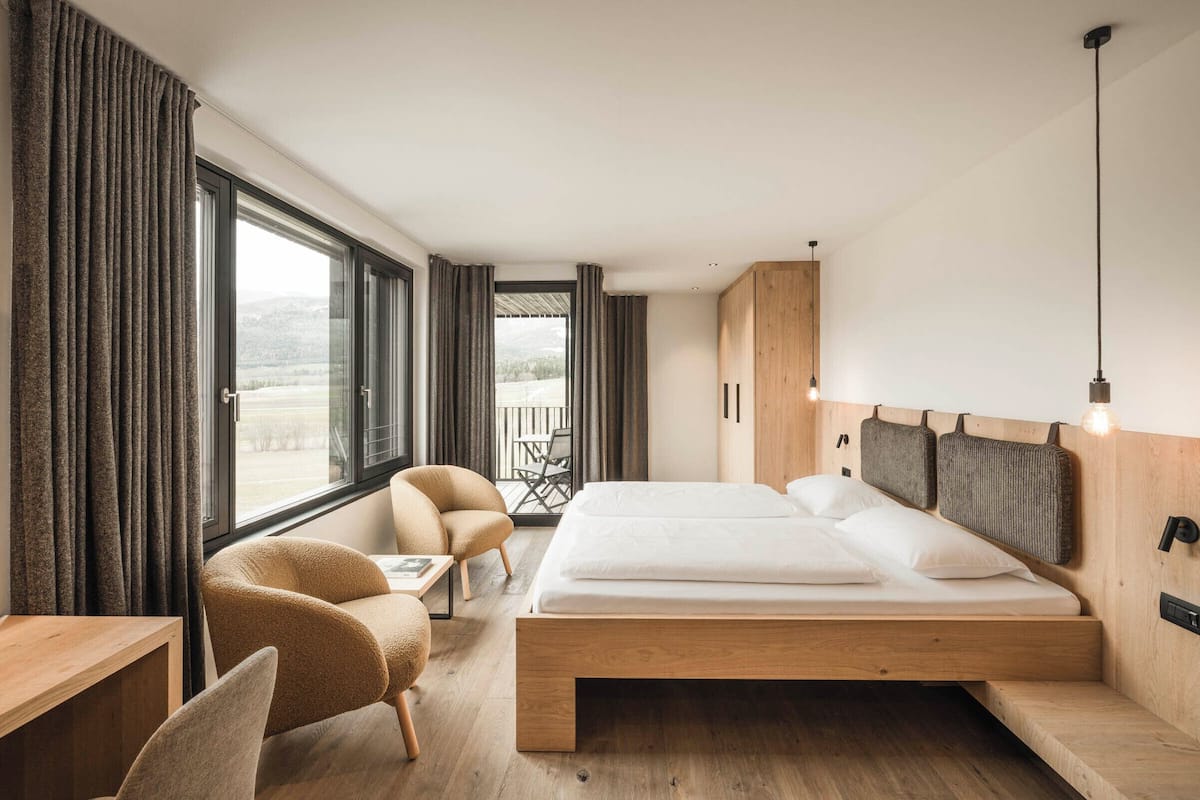 Een slaapkamer met een bed, een stoel, een bureau en uitzicht op de omgeving.