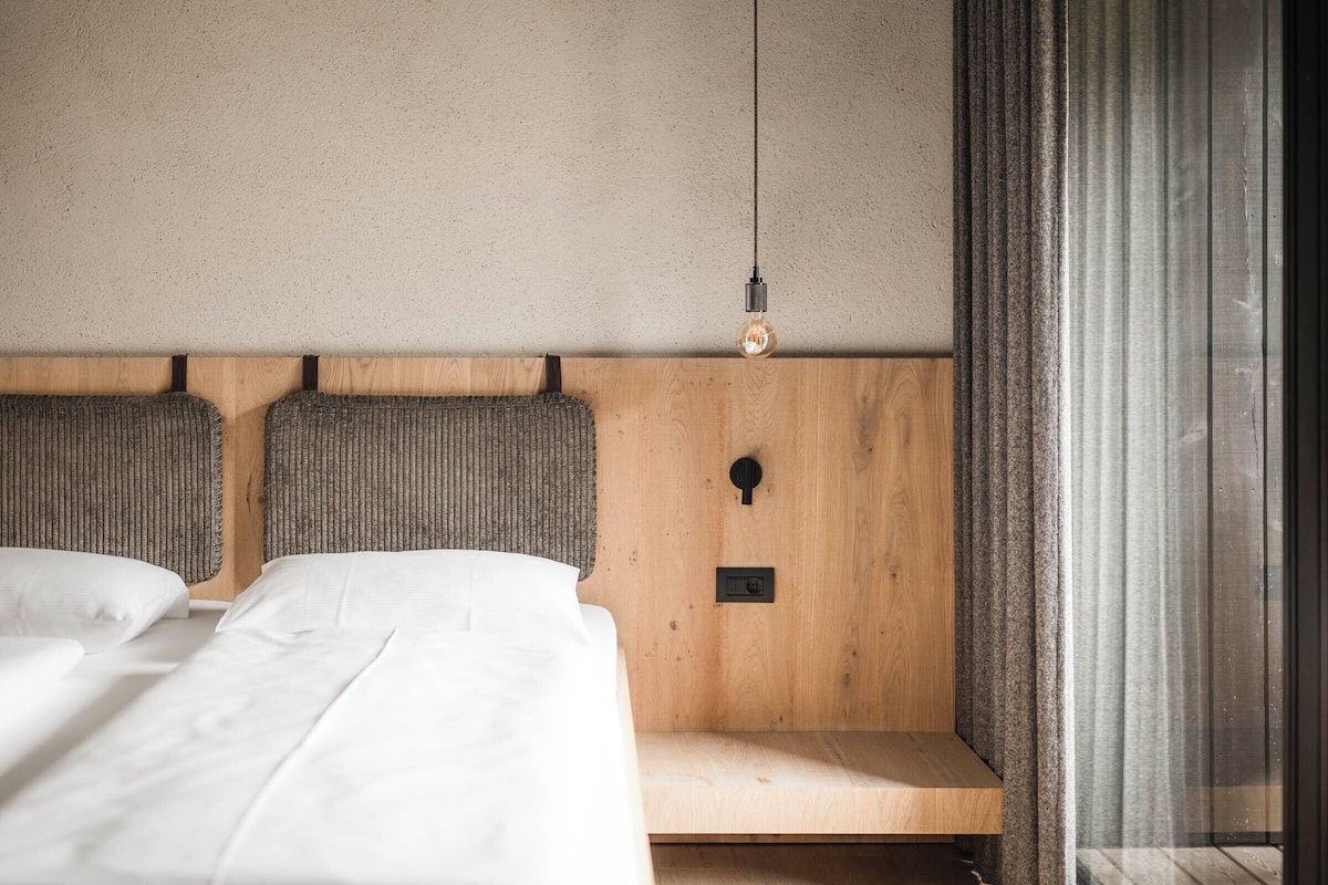 Een slaapkamer met een houten hoofdbord, een nachtkastje en een hanglamp.