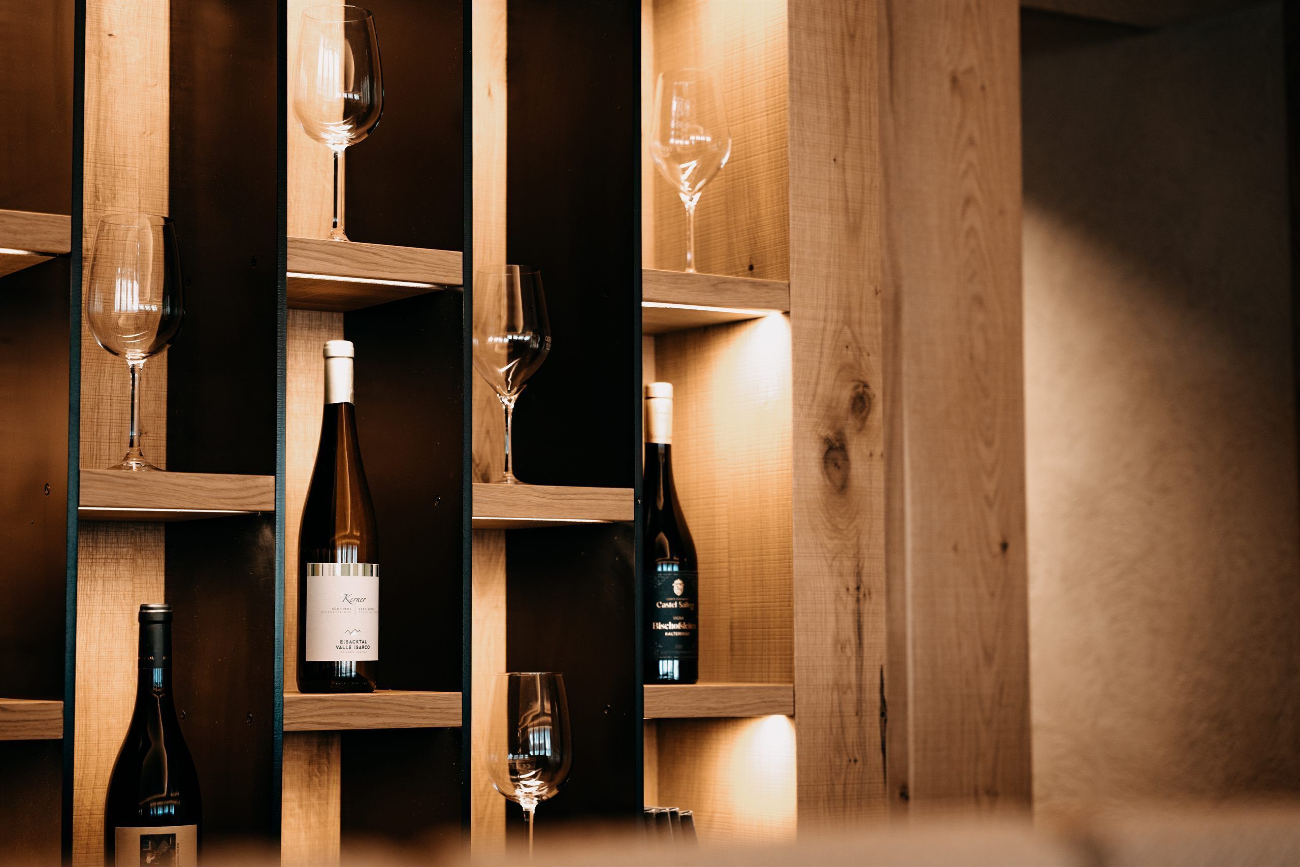 Una botellera de madera con botellas y copas.