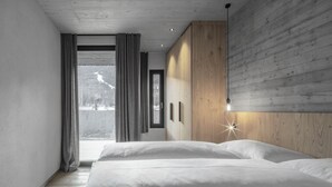 Un dormitorio moderno con una cama grande, un panel de pared de madera y vistas a un paisaje nevado.