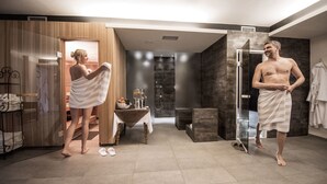Un baño moderno con sauna de madera, cabina de ducha de vidrio y una mesa con artículos de aseo.