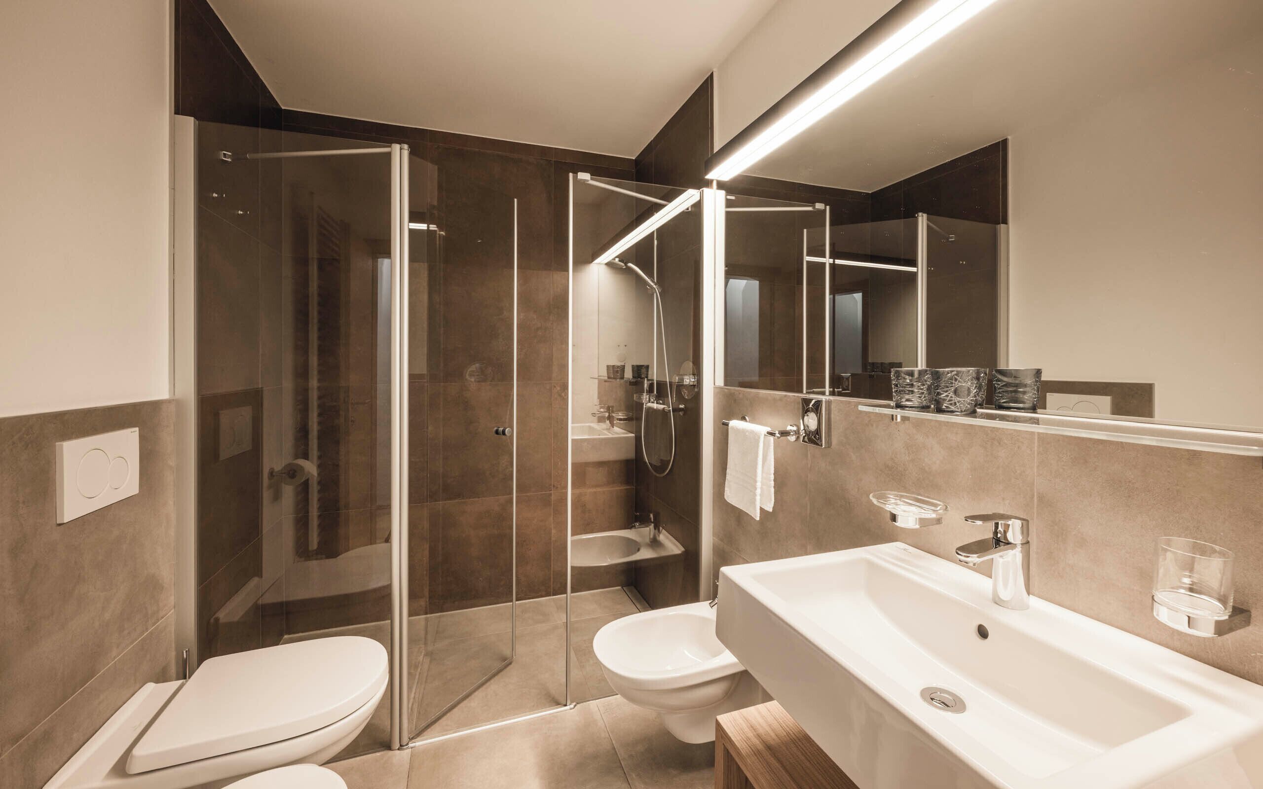 A modern bathroom with a glass-enclosed shower, a white sink, and a toilet.