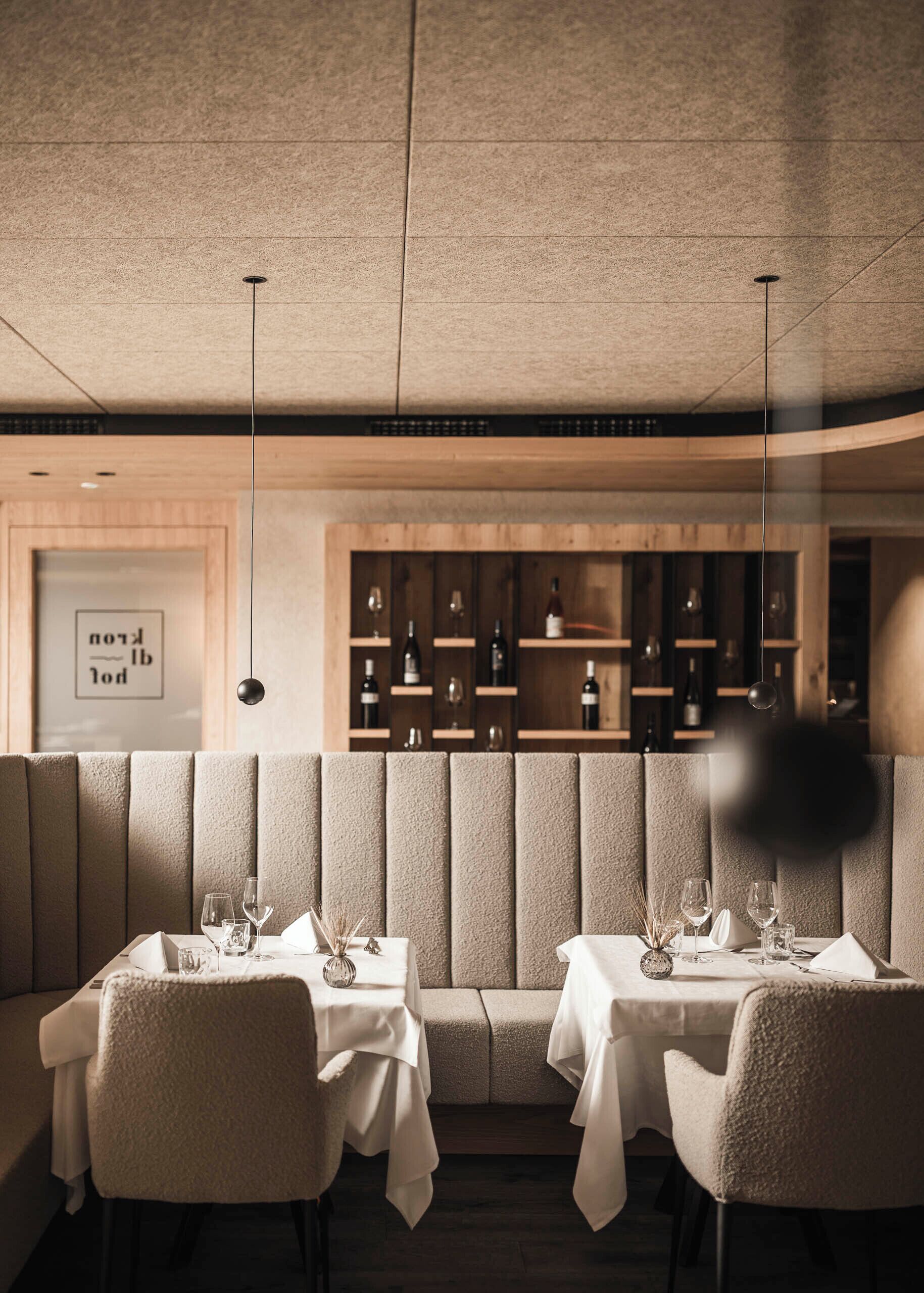 A restaurant with booth seating, tables, and a wine display.