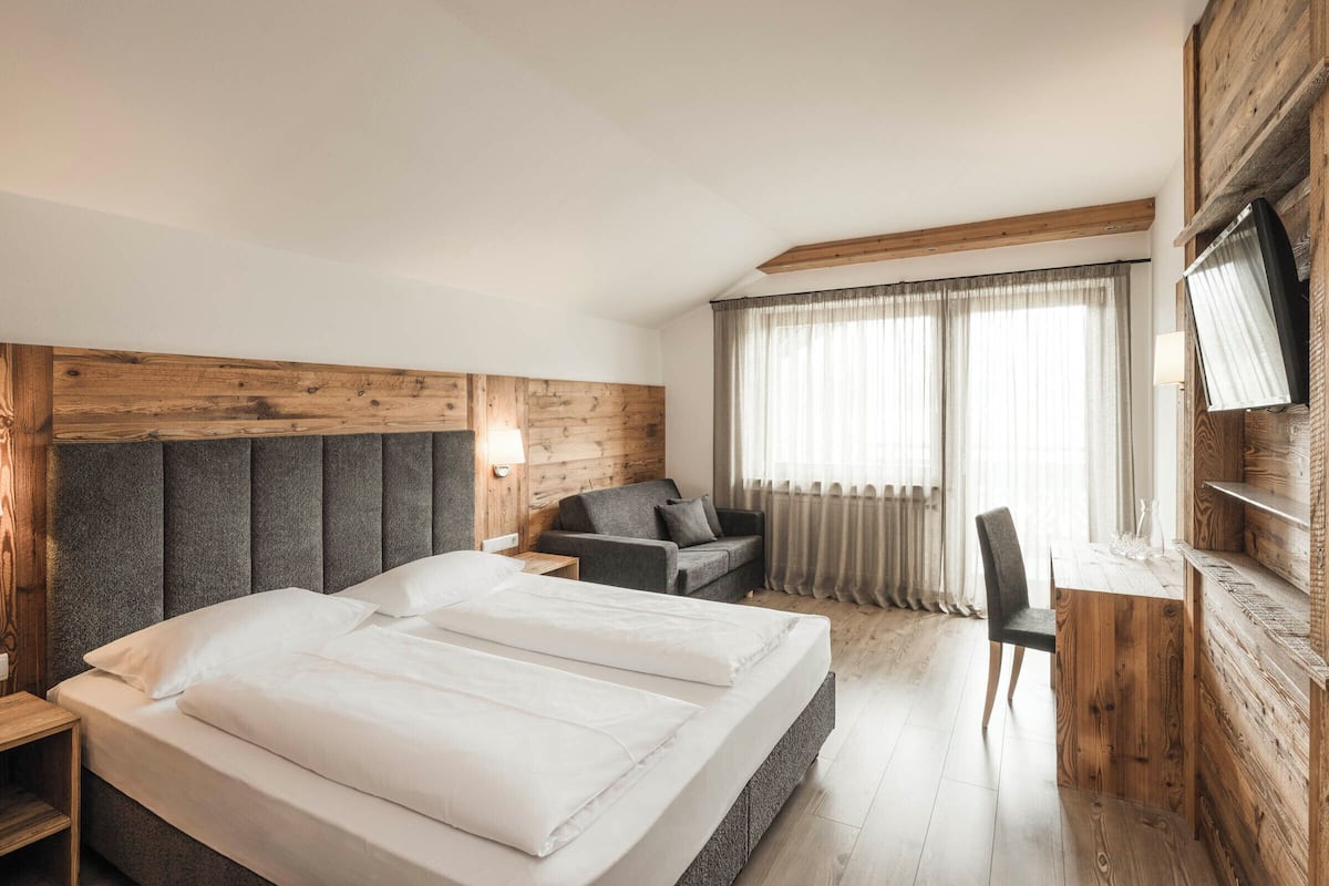 Een hotelkamer met een groot bed, een bank, een bureau en een televisie aan de muur.