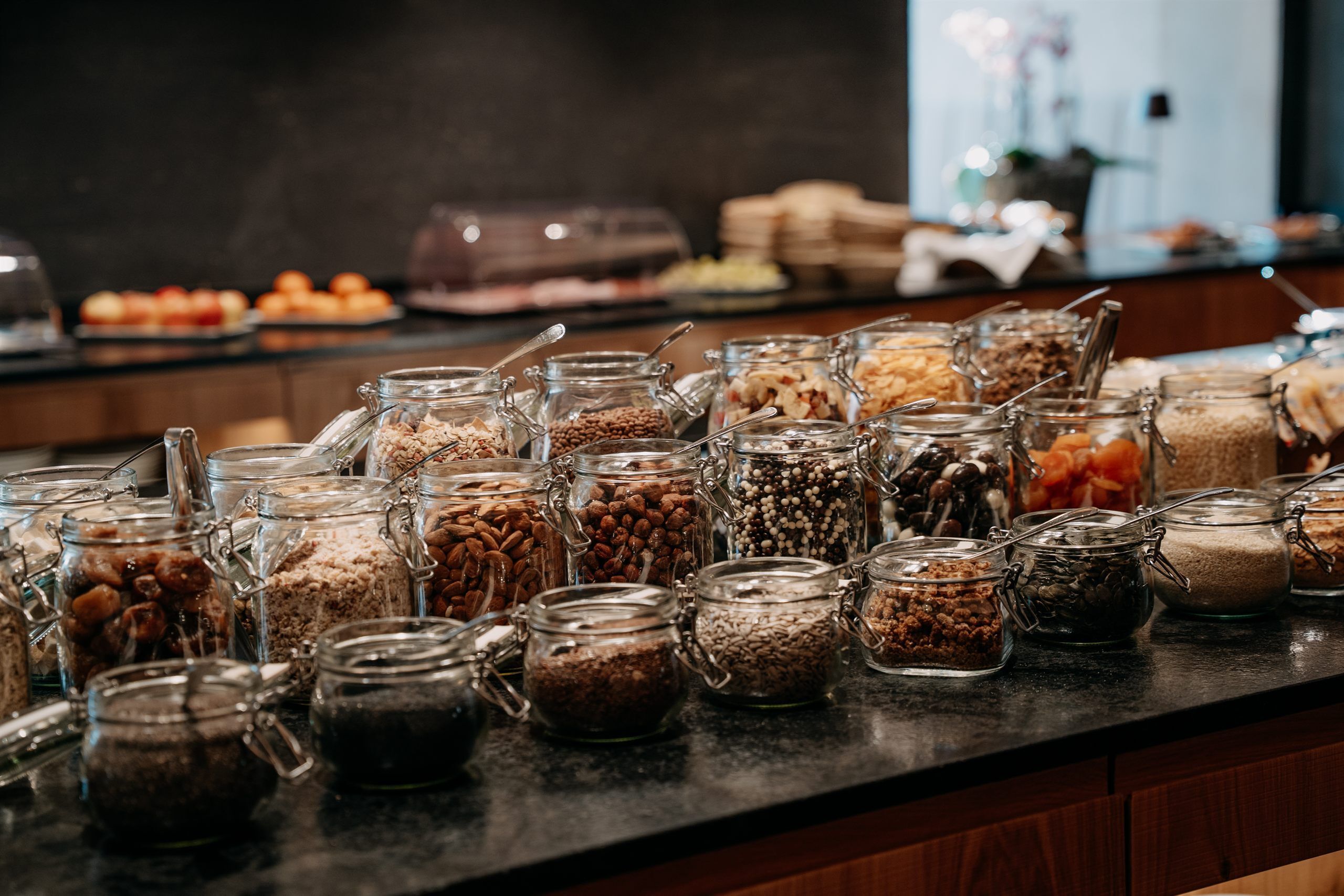 Un bufé con distintos alimentos presentados en frascos de vidrio.