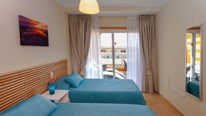 A hotel room with two beds, a painting on the wall, a balcony with a view, and a window with curtains.