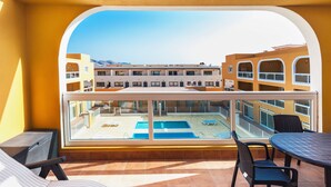 A balcony with a view of a swimming pool and a building complex.