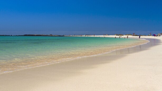 A wide, sandy beach with clear turquoise water.