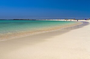 Una playa amplia y arenosa con agua turquesa cristalina.