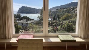 A room with a large window offering a view of a lake and hills. There is a bed with a pink blanket and a green blanket on a bench. - Superb modern Family Villa nearby fabulous sandy beaches (Rayol-Canadel-Sur-Mer)