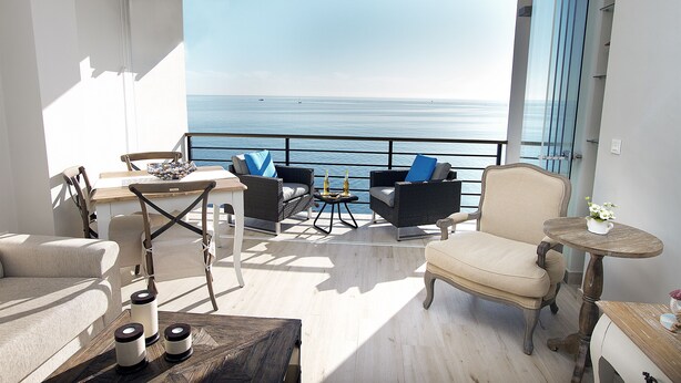 A balcony with a view of the sea, furnished with a sofa, chairs, and a small table. - DELUXE APARTMENT- BEACHFRONT, SWIMMING POOL, A/A, FREE WIFI AND PARKING (Torremolinos)