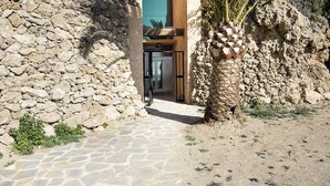 A stone pathway leading to a building with a modern entrance and a stone wall on one side. - DELUXE APARTMENT- BEACHFRONT, SWIMMING POOL, A/A, FREE WIFI AND PARKING (Torremolinos)