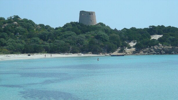 A beach with clear turquoise water, a sandy shore, and a castle on a hill in the background. - Apartment/ flat - Villasimius (Castiadas)