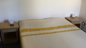 A hotel room with a bed, two nightstands, and a door. - Apartment/ flat - Villasimius (Castiadas)