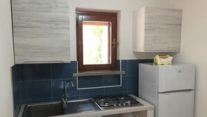 A compact kitchen with a gas stove, sink, and a built-in oven. - Apartment/ flat - Villasimius (Castiadas)