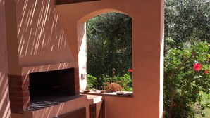 An outdoor kitchen area with a built-in oven, a wooden cabinet, and a brick floor. - Apartment/ flat - Villasimius (Castiadas)