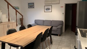 A dining area with a wooden table and black chairs, a gray sofa, and a staircase with wooden railings. - 3 bedroom villa, sea 5 minutes walk, private parking & garden, quiet location (Ulica Bana  Mazuranica)