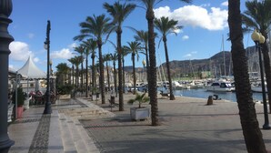 Eine Uferpromenade mit Palmen, ein Yachthafen mit Booten und einem strahlend blauen Himmel.