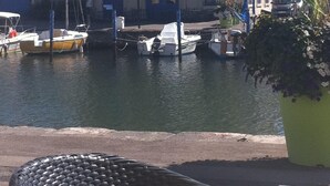 Un bâtiment historique doté d’un balcon, d’un drapeau et d’une rangée de bateaux amarrés sur l’eau.