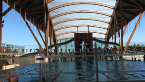 Une piscine intérieure dotée d’une grande structure de toit incurvée.