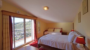 A bedroom with two beds, a large window with curtains, a nightstand with a lamp, and a view of a hilly landscape. - Breathtaking Views Holiday House with Heat and or Air conditioning System (Arco da Calheta)