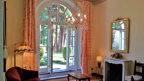 A room with a large arched window, a chandelier, a fireplace, and two armchairs. - Apartment with private Italian-style garden, a few steps from the lake. (Bellagio)